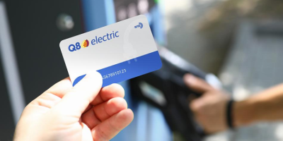 personne qui tient un carte Q8 electric dans sa main