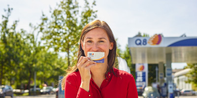 Vrouw die een Q8 smiles kaart voor haar mond houdt
